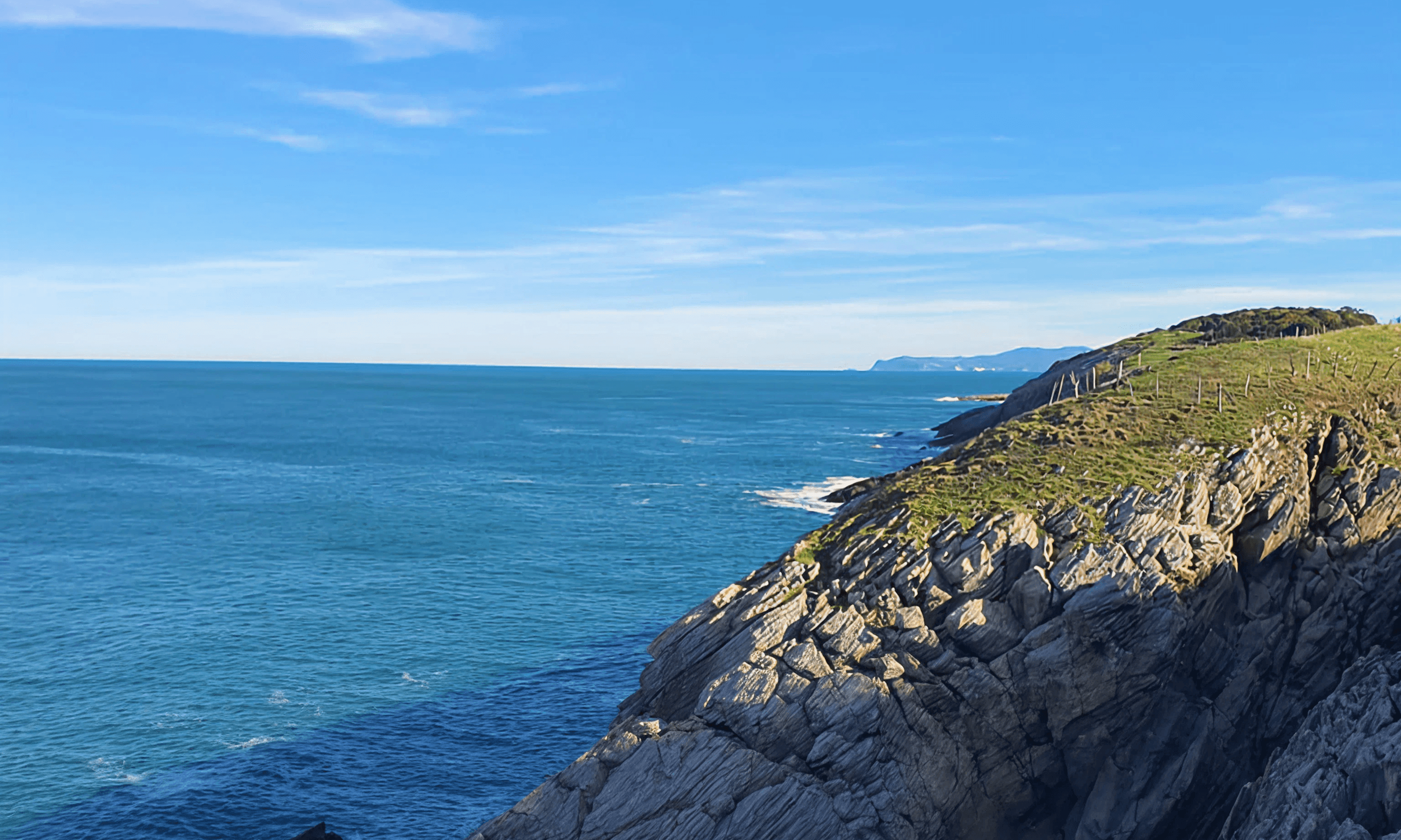 Costa abierta del Cantábrico con relieve verde y horizonte amplio